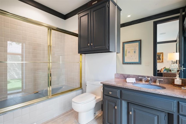 full bathroom with ornamental molding, bath / shower combo with glass door, vanity, wood-type flooring, and toilet