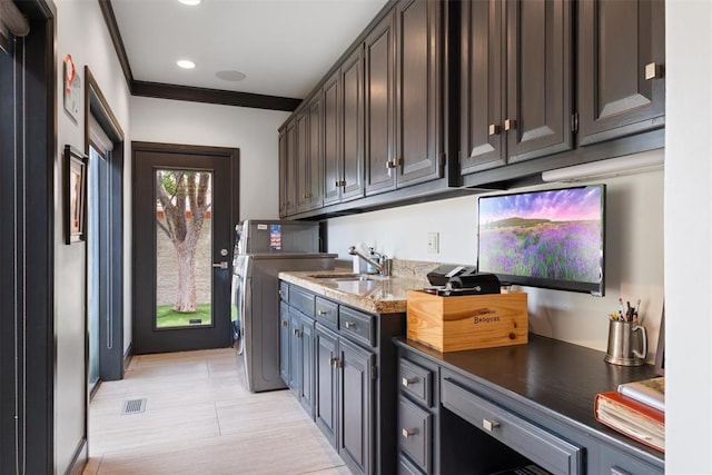 kitchen with dark brown cabinets, crown molding, light stone countertops, and sink