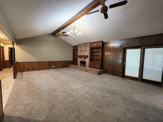 unfurnished living room featuring light carpet, a brick fireplace, ceiling fan with notable chandelier, vaulted ceiling with beams, and wood walls