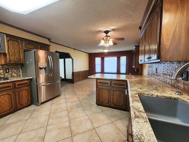 kitchen with ceiling fan, sink, stainless steel fridge, crown molding, and decorative backsplash