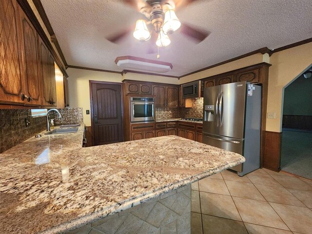 kitchen with ceiling fan, sink, kitchen peninsula, appliances with stainless steel finishes, and ornamental molding