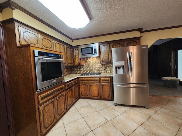 kitchen with appliances with stainless steel finishes, a textured ceiling, light tile patterned floors, and crown molding