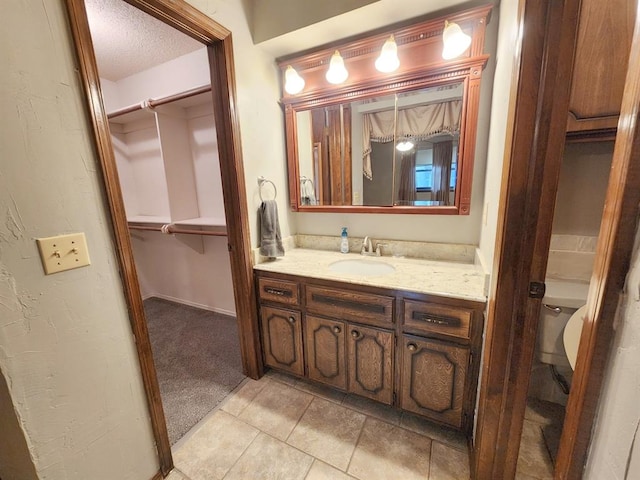 bathroom featuring vanity, tile patterned floors, a textured ceiling, and toilet