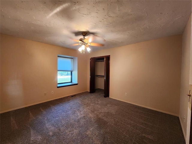 unfurnished bedroom featuring dark carpet and ceiling fan