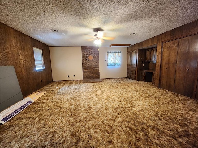 empty room featuring carpet, ceiling fan, a textured ceiling, and wooden walls