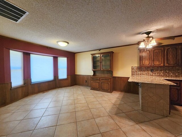 1116 Reid Cir, Seminole, OK 74868 - kitchen with a wainscoted wall, a peninsula, wood walls, brown cabinets, and glass insert cabinets