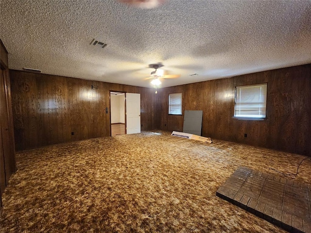 1116 Reid Cir, Seminole, OK 74868 - spare room with carpet flooring, ceiling fan, wooden walls, and a textured ceiling