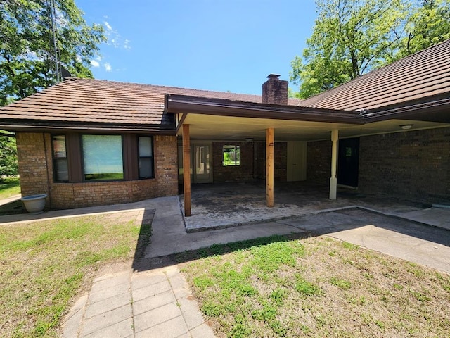 1116 Reid Cir, Seminole, OK 74868 - rear view of house featuring a chimney, brick siding, driveway, a patio area, and an attached carport
