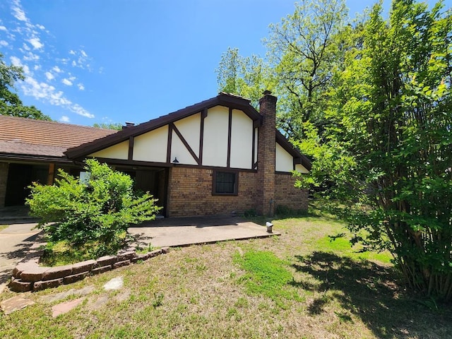 1116 Reid Cir, Seminole, OK 74868 - view of side of home featuring a chimney, a patio, brick siding, and a lawn