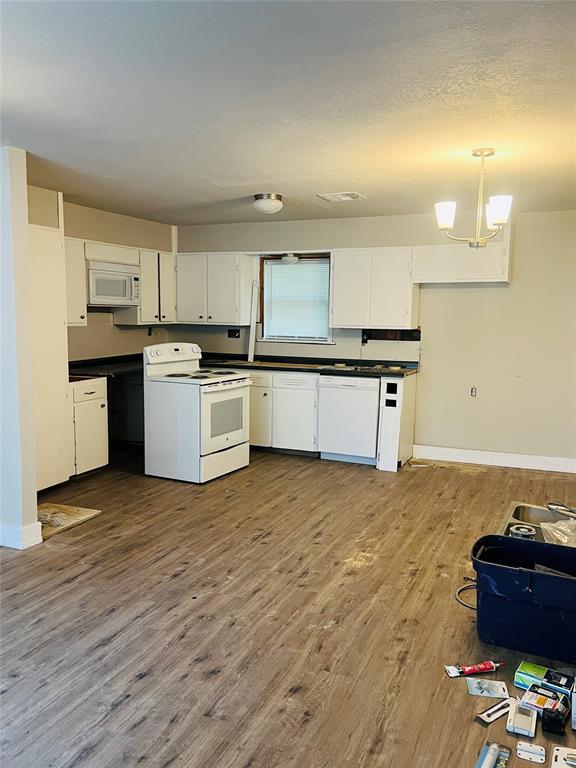 kitchen with white cabinets, decorative light fixtures, wood-type flooring, and white appliances