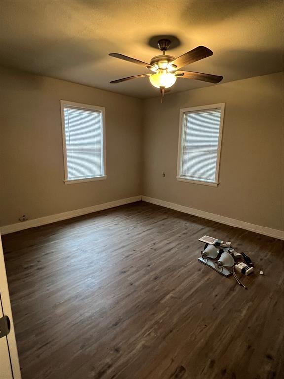 spare room with ceiling fan, a healthy amount of sunlight, and dark wood-type flooring