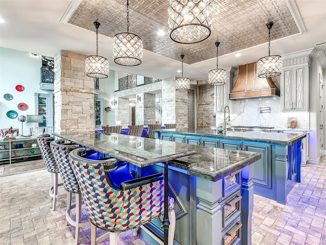 kitchen featuring pendant lighting, premium range hood, a kitchen breakfast bar, dark stone countertops, and kitchen peninsula