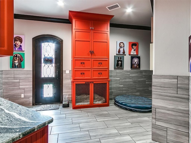 interior space featuring ornamental molding and tile walls