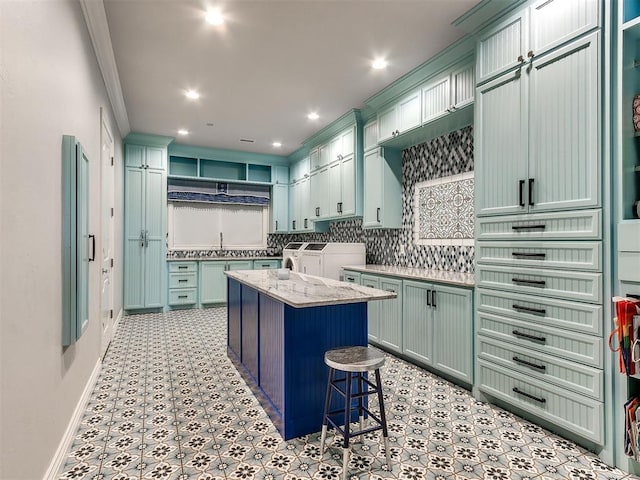 kitchen with washer and dryer, light stone countertops, tasteful backsplash, a kitchen island, and a breakfast bar area