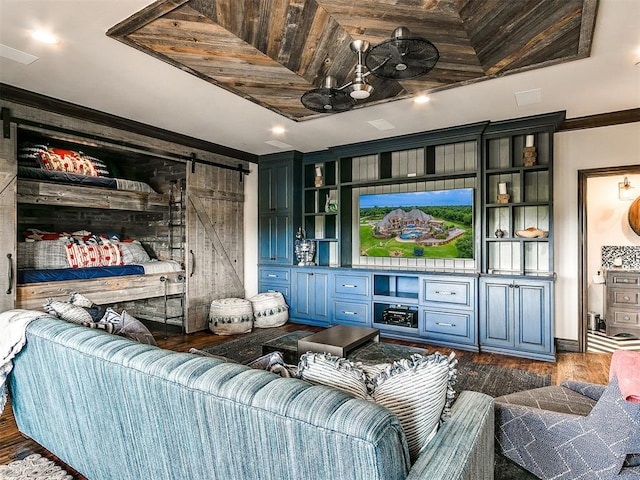 cinema room with ornamental molding, a barn door, and dark wood-type flooring