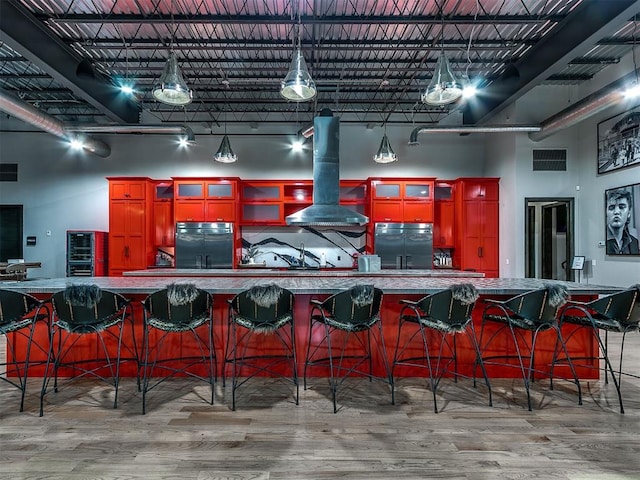 kitchen featuring black refrigerator, stainless steel fridge, a spacious island, exhaust hood, and hardwood / wood-style floors