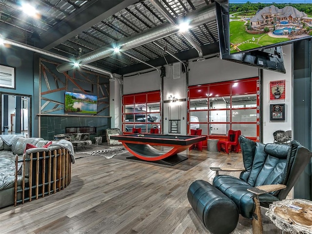 playroom with hardwood / wood-style floors, a towering ceiling, and billiards