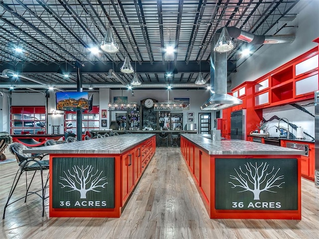 interior space with hardwood / wood-style flooring, a center island, built in fridge, and island range hood