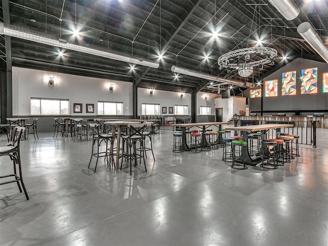 dining area featuring high vaulted ceiling and concrete flooring