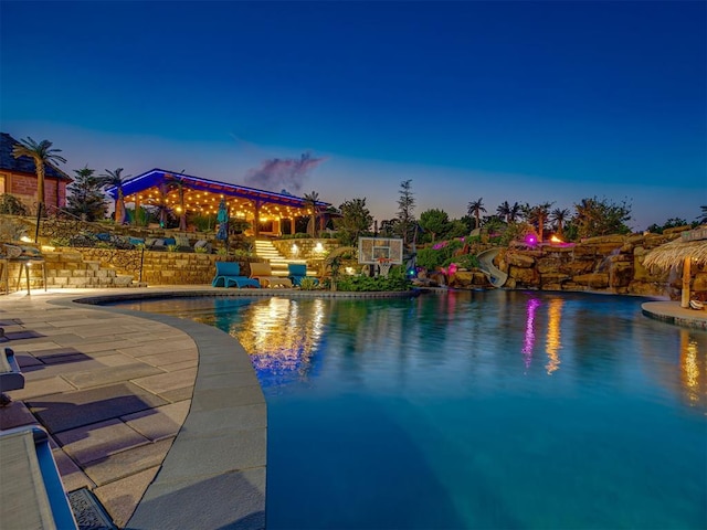 pool at dusk featuring a patio and a water slide