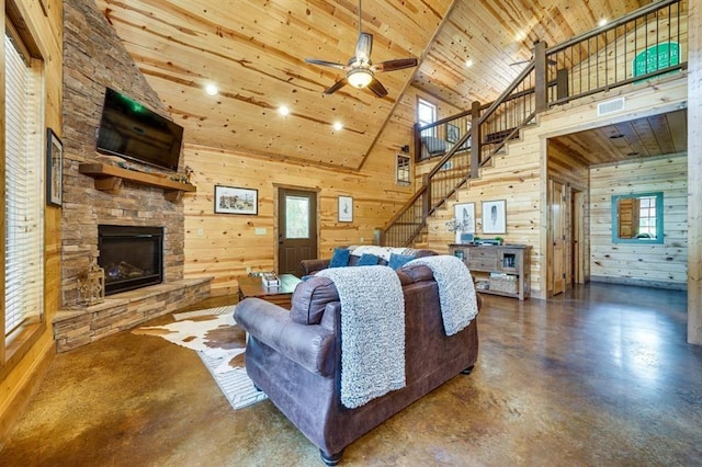 living room with ceiling fan, wooden ceiling, concrete flooring, wooden walls, and a fireplace