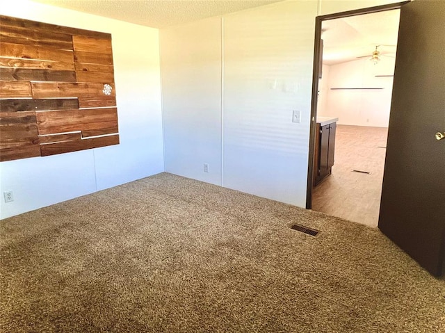 carpeted spare room featuring ceiling fan and a textured ceiling