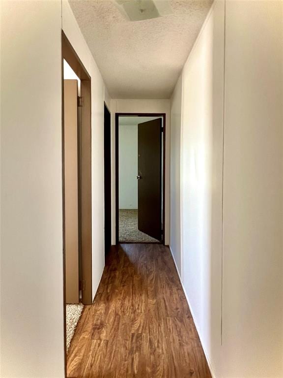 hall with a textured ceiling and dark wood-type flooring