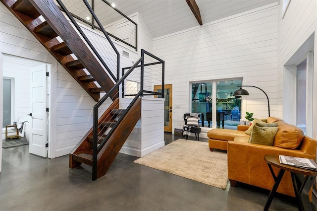 interior space featuring wooden walls, beam ceiling, and high vaulted ceiling