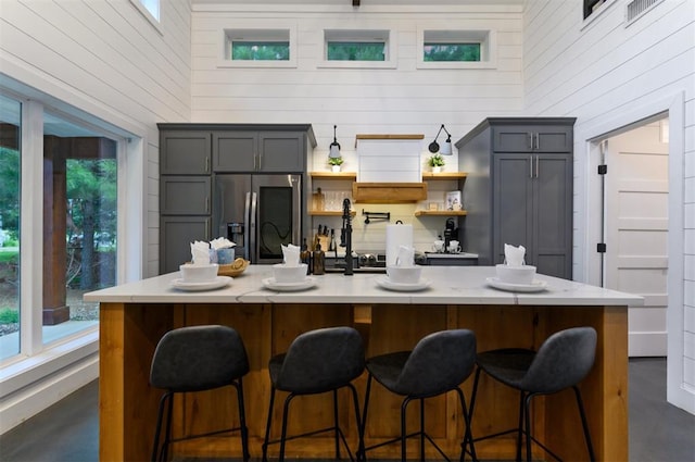 kitchen featuring plenty of natural light, gray cabinets, stainless steel refrigerator with ice dispenser, and a high ceiling