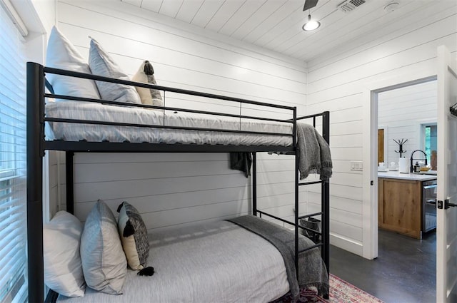 bedroom with wooden ceiling, wooden walls, and sink