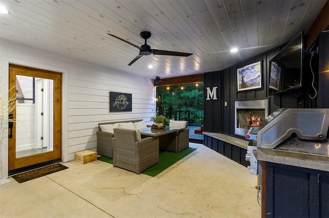 view of patio / terrace featuring an outdoor living space with a fireplace, ceiling fan, and exterior kitchen