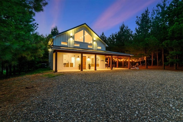 back house at dusk featuring covered porch