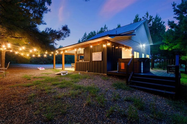 property exterior at dusk featuring a wooden deck and a hot tub