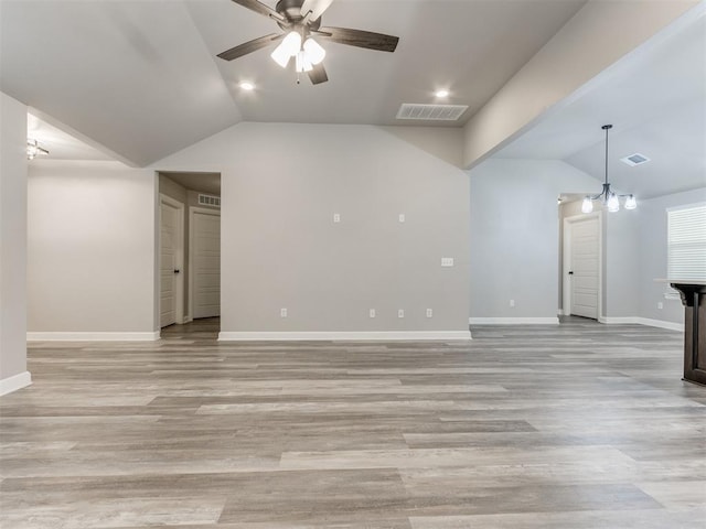 interior space featuring ceiling fan with notable chandelier, light wood-type flooring, and vaulted ceiling