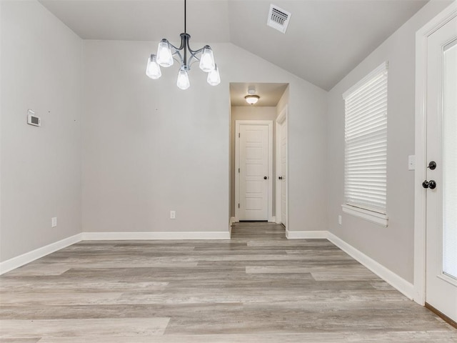 unfurnished dining area with light hardwood / wood-style floors, lofted ceiling, a healthy amount of sunlight, and an inviting chandelier