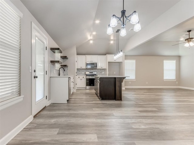 kitchen featuring pendant lighting, lofted ceiling, light wood-type flooring, appliances with stainless steel finishes, and white cabinetry