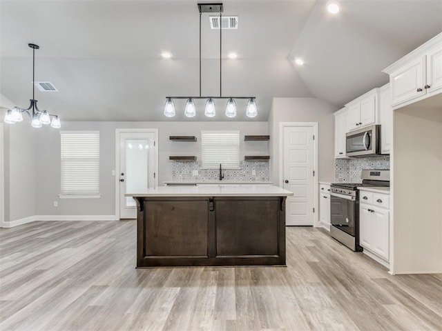 kitchen featuring white cabinets, appliances with stainless steel finishes, light hardwood / wood-style flooring, and vaulted ceiling