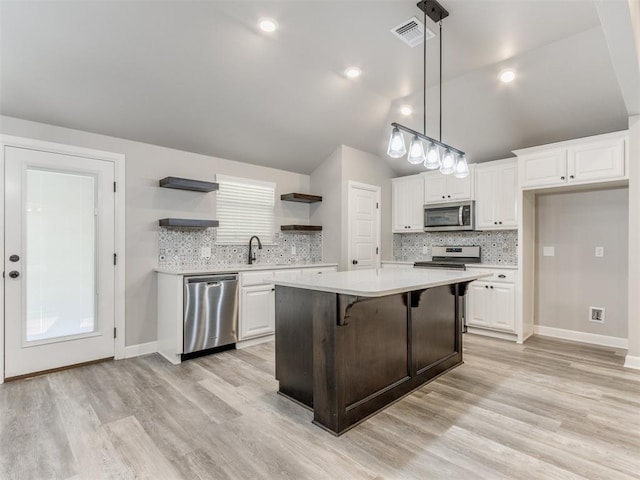 kitchen with pendant lighting, a center island, light hardwood / wood-style flooring, white cabinetry, and stainless steel appliances