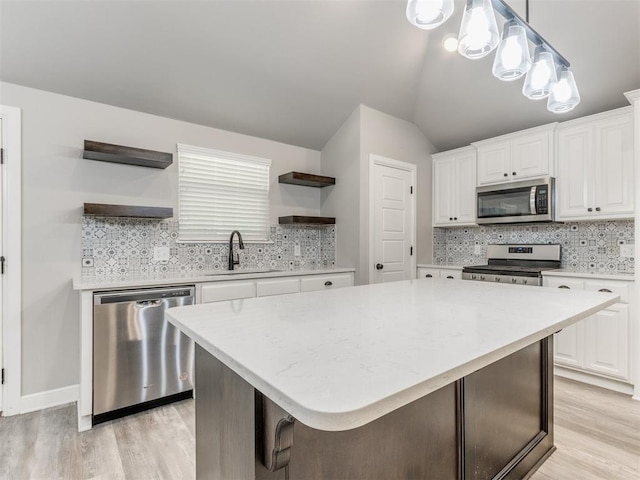 kitchen with backsplash, white cabinets, a kitchen island, and appliances with stainless steel finishes