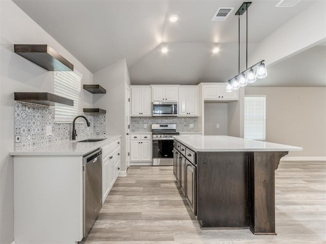 kitchen featuring stainless steel appliances, white cabinetry, tasteful backsplash, and lofted ceiling