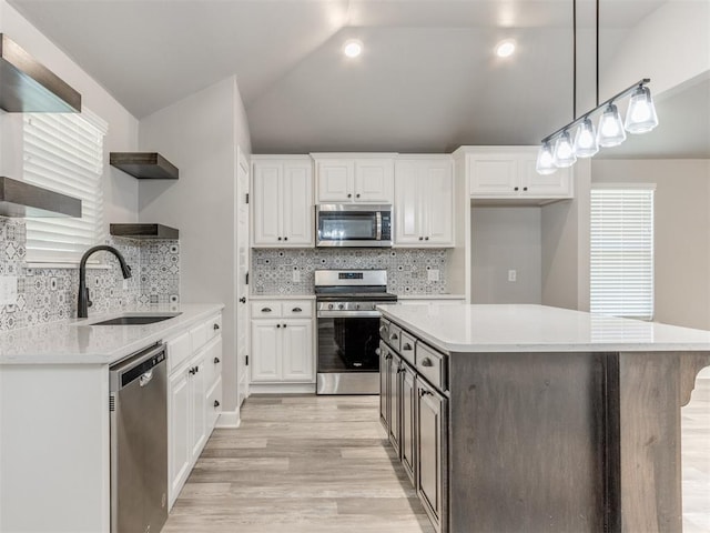 kitchen featuring appliances with stainless steel finishes, backsplash, sink, white cabinets, and a center island