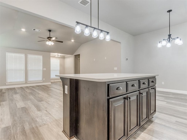 kitchen with a center island, pendant lighting, vaulted ceiling, light hardwood / wood-style floors, and ceiling fan with notable chandelier