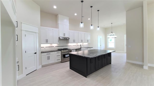 kitchen with a center island, white cabinets, light hardwood / wood-style flooring, stainless steel range, and decorative light fixtures