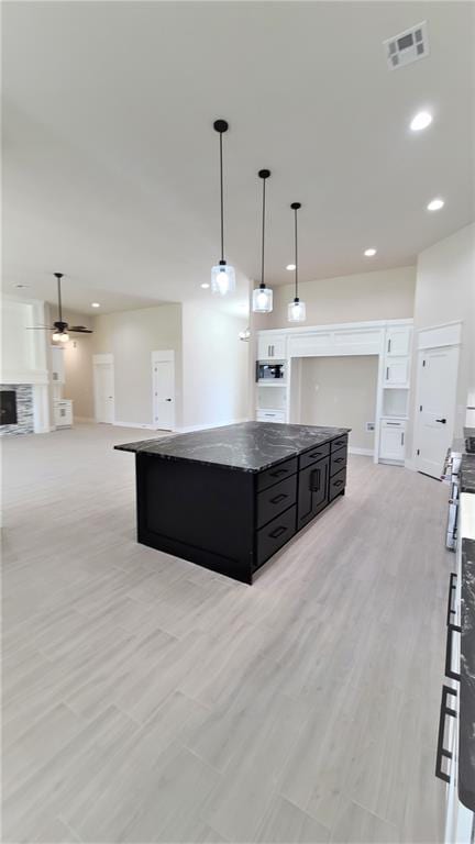 kitchen featuring ceiling fan, a center island, pendant lighting, and light hardwood / wood-style flooring