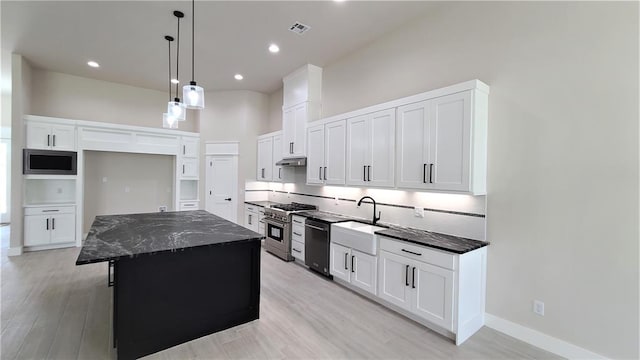 kitchen featuring stainless steel appliances, sink, white cabinetry, a kitchen island, and hanging light fixtures