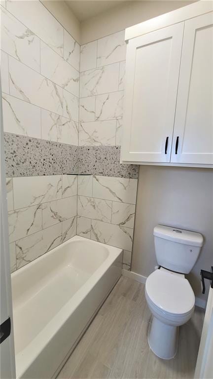 bathroom with hardwood / wood-style flooring, toilet, and tiled shower / bath