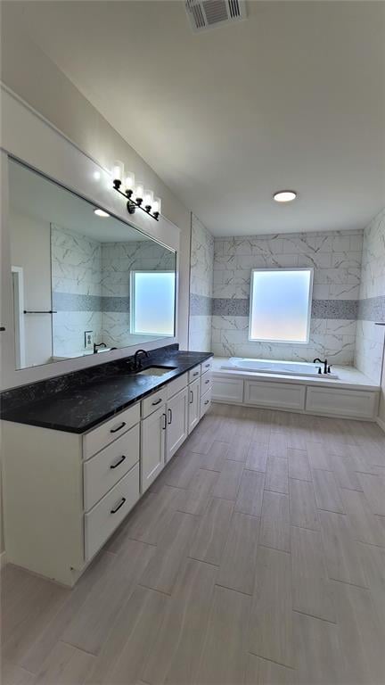 bathroom featuring a washtub, wood-type flooring, and vanity