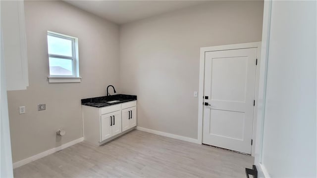 laundry area featuring hookup for an electric dryer, light hardwood / wood-style floors, cabinets, and sink