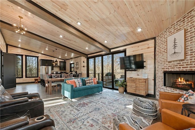 living room featuring hardwood / wood-style floors, lofted ceiling with beams, a brick fireplace, a notable chandelier, and wood ceiling