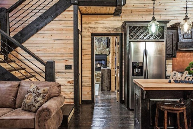 interior space with stainless steel fridge, wood walls, and decorative light fixtures